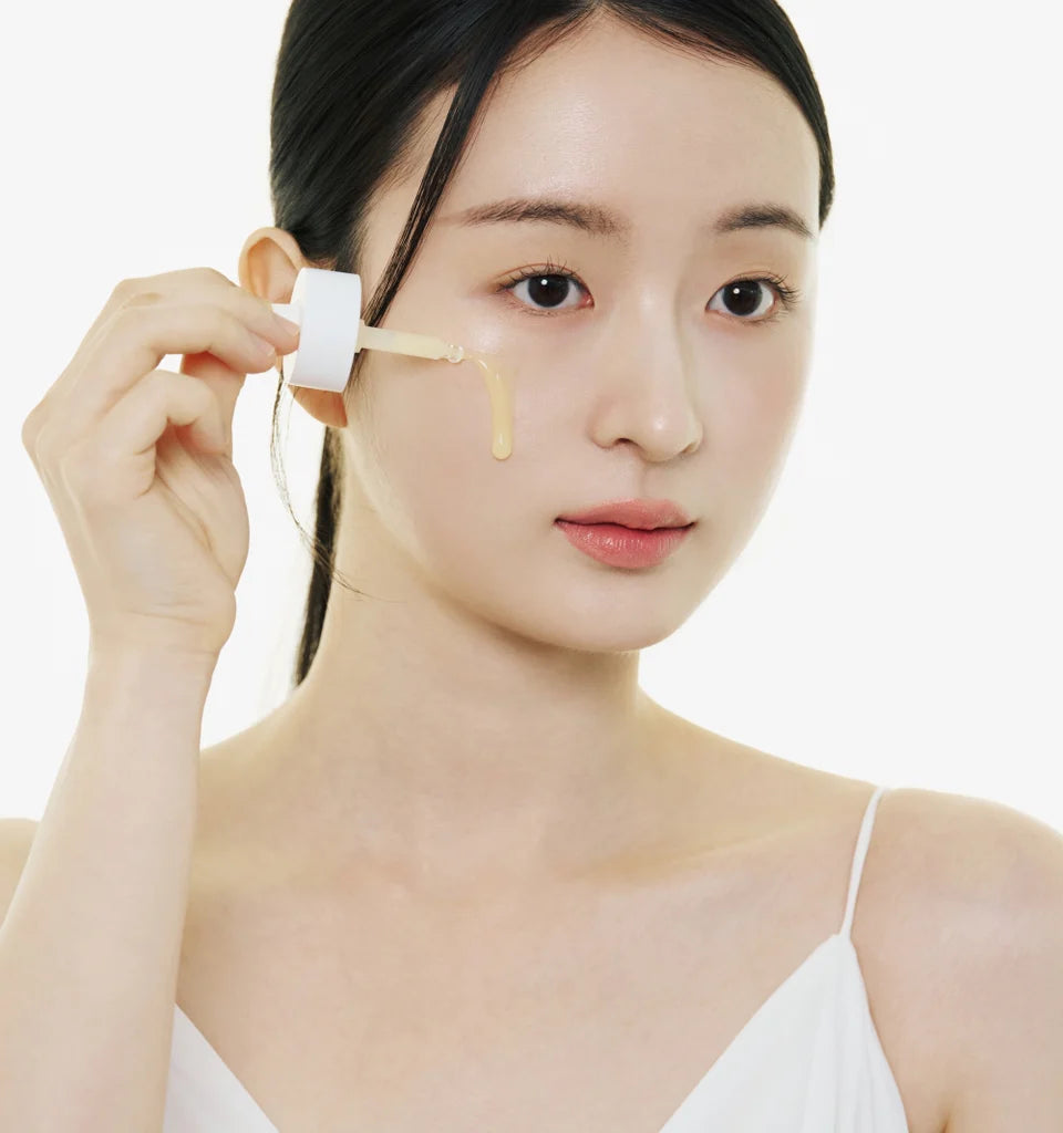 Woman applying a cosmetic product to her face with a brush on a white background