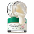 A jar of AXIS-Y Dark Spot Correcting Glow Cream with a green lid, shown with another jar tipped over pouring the cream onto the front jar. The cream is thick and off-white, and the background is solid white.