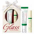 AXIS-Y Glass skincare gift set featuring a cream-colored gift box with a white ribbon, a tube of Dark Spot Correcting Glow Serum, a tube of Brightening Care Glow Serum, and a tube of Vitamin Cellulose Cream, all on a white background.