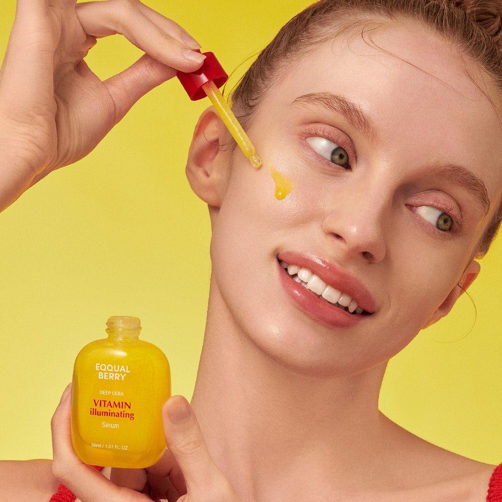 Woman applying a yellow skincare product to her face with a dropper against a yellow background